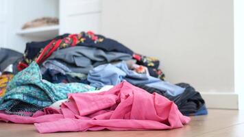 A Chaotic and Messy Pile of Various Colorful Clothes Scattered on a WellWorn Wooden Floor Surface video