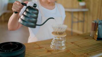 Pour Over Coffee Brewing Method. Close-up of hands carefully pouring hot water from a gooseneck kettle into a pour-over coffee dripper, showcasing the meticulous process of crafting a perfect cup. video