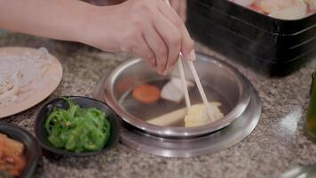 Sizzling Hot Pot, A close-up shot of a hand using chopsticks to stir a hot pot with various ingredients, creating a mouthwatering scene of Asian cuisine. video