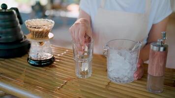 Ice Coffee Preparation. Close-up of hands adding ice to a glass, showcasing the meticulous process of crafting a refreshing iced coffee. video