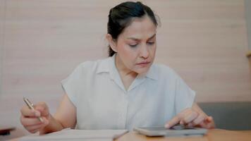 Focused Woman Calculating Expenses. A detail-oriented woman meticulously works on her finances, using a calculator and notebook. The image conveys concentration and careful planning. video