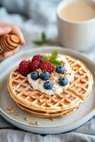 Delicious breakfast featuring a waffle topped with berries and honey served with coffee photo