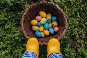 Child holding a basket of colorful Easter eggs in the garden during springtime photo