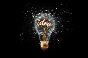 Creative idea light bulb with Idea explodes with shards of glass on a dark background. Business, ideas and new thinking. Think Different. Go beyond what is possible. Marketing. Creative thinking photo