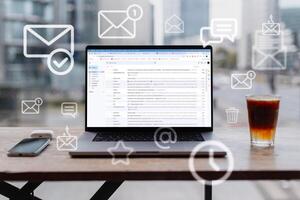 Laptop with open webmail service site and flying mail icons in office stands on table on a urban background. Mail and work, concept. Incoming mail, creative idea photo
