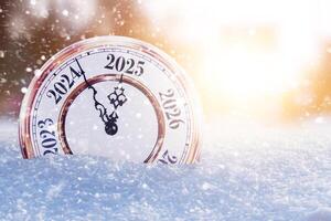 Vintage clock in the snow and points to the new year 2025. Beautiful winter background with sunset and lights. New Year and Christmas Countdown, creative idea. photo
