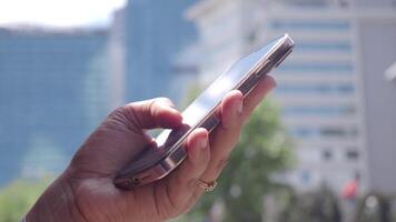 A closeup view of a hand interacting with a smartphone in an urban setting video