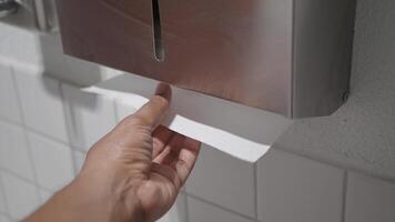 Hand Using Paper Towel Dispenser in a Hygienic Public Restroom with Clean White Tiles video