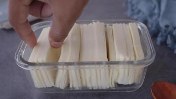 mão fatiamento e armazenando fatiado queijo dentro uma vidro recipiente video