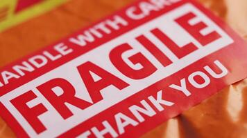 A cardboard box marked with a caution label for fragile goods handling during shipping video