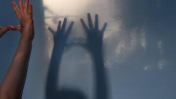 Blur shadows of child hands on wall. Game with light and shadow. Dark spooky silhouettes of hands for Halloween concept video