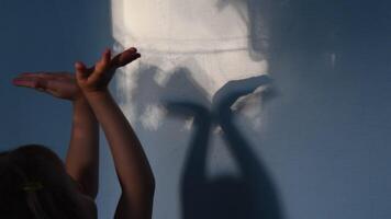 Child claps hands on unfocused foreground and focus to blurry hand shadows on wall background. Game with light and shadow. Dark spooky silhouettes of hands for Halloween concept video