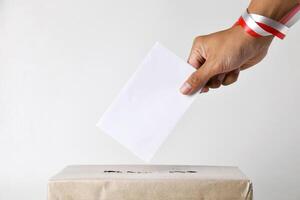 Hands using red and white ribbons insert ballot papers into ballot boxes photo