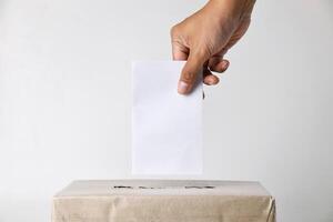 Closeup photo of hands inserting ballot paper into a cardboard ballot box
