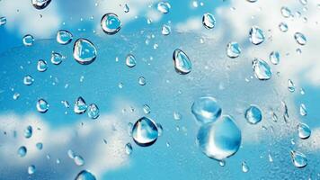 Close up of transparent water drops clinging to a glass surface against a background of serene blue sky and white clouds, creating a refreshing and pure visual video