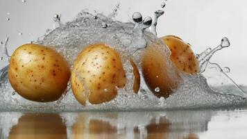 Three potatoes create a lively and invigorating sight as they are washed, making a splash by water against a white background video