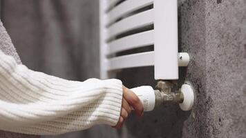 Temperature on a radiator thermostat, regulating home heating for energy efficiency. Hand Adjusting Temperature On Thermostat To Control Heat In Central Home Heating System. Banner, free copy space video