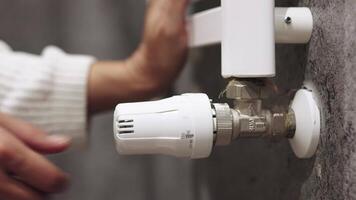 Temperature on a radiator thermostat, regulating home heating for energy efficiency. Hand Adjusting Temperature On Thermostat To Control Heat In Central Home Heating System. video
