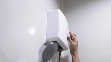 A woman's hand turning on an instant water heater in the shower. Concept of using modern energy-efficient technologies for comfort and resource savings. Banner, free copy space video