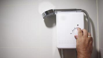 Man hand turns on the water heater temperature regulator. Water temperature in the electric boiler. Concept of energy-efficient technologies, modern comfort, and energy saving. Free copy space, banner video