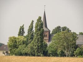 A church with a steeple and trees in the background at bislich photo