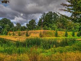 A grassy field with trees and a hill photo