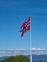 A blue sky with white clouds and a norwegian banner photo