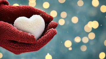 Red knitted woolen gloves holding a glowing snow heart against a blurred winter background with warm bokeh lights and falling snowflakes video