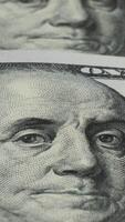 A close-up view of Benjamin Franklin's portrait on the hundred dollar bills reveals the fine details of the engraving and the texture of the paper. Vertical footage video