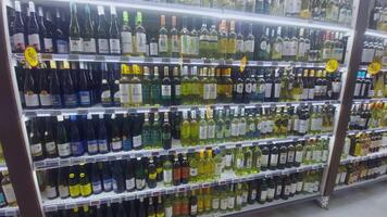 KYIV, UKRAINE - DEC 22, 2024. Shelves filled with an extensive selection of wine bottles in a store, showcasing different brands and varieties, illuminated by bright lights for easy browsing. video