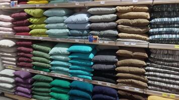 KYIV, UKRAINE - DEC 22, 2024. Rows of neatly arranged cushions in diverse colors and textures fill the shelves of a home goods store. Shoppers can explore options for home decoration and comfort. video
