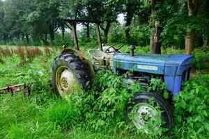 An old tractor is sitting in the grass photo