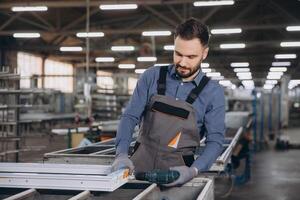 Factory worker assembling aluminum and pvc window frames in workshop photo