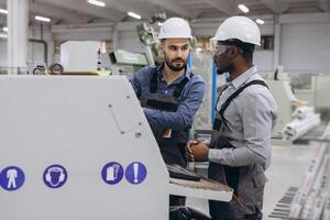 Engineers discussing while operating industrial machinery for PVC windows and doors production photo