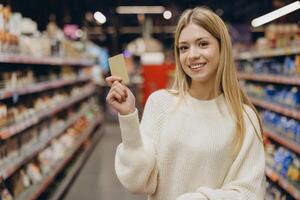 Smiling woman showing loyalty card in supermarket photo