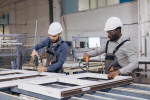 Factory workers assembling PVC window frames on production line photo