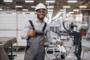 Factory worker making thumb up gesture while operating industrial machine for PVC windows and doors production photo