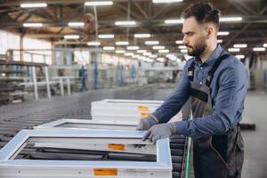 Factory worker checking PVC window frames on production line photo