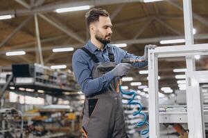 Factory worker assembling pvc window frame using pneumatic screwdriver photo