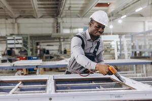 Factory worker assembling pvc window frame using pneumatic screwdriver photo