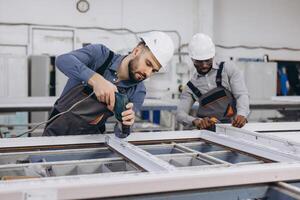 Factory workers assembling PVC window frames in production line photo