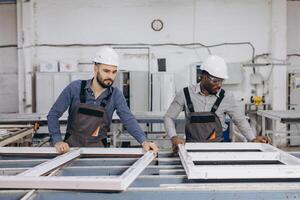 Factory workers assembling pvc window frames in production line photo