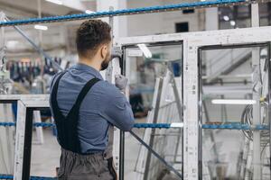 Factory worker assembling aluminum and pvc window frame in production line photo