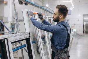 Factory worker measuring PVC window frame in production line photo