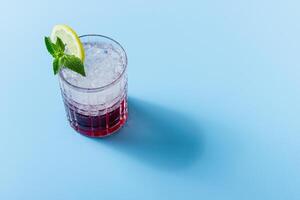 Cocktail with ice in a glass with copy space on a blue background photo