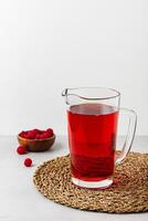 Red color drink in the glass jug on gray background. photo