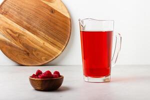 Red color drink in the glass jug on gray background. photo