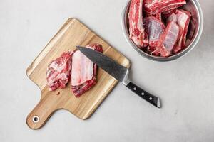 Raw beef ribs on wooden cutting board with knife photo