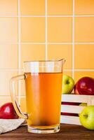 Apple cider in a glass jug on a wooden table photo