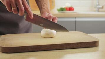 male chef slices mushrooms in close-up on a chopping board in a home kitchen. video